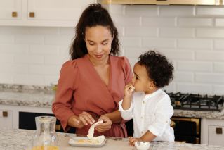 Mother and son preparing food together in a modern kitchen setting. Family bonding time.